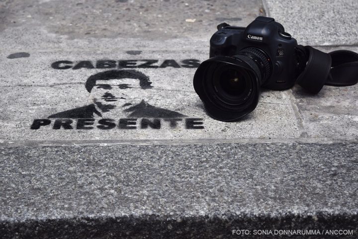 Una cámara de fotos sobre el pavimento de una calle, que tiene la imagen en aerosol de Cabezas