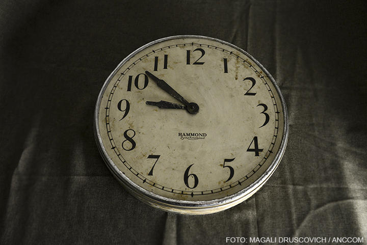 Un reloj de pared marca Hammon, con el borde de color plata y el interior amarillo por el paso del tiempo. Las agujas del reloj marcan las 9:53. 