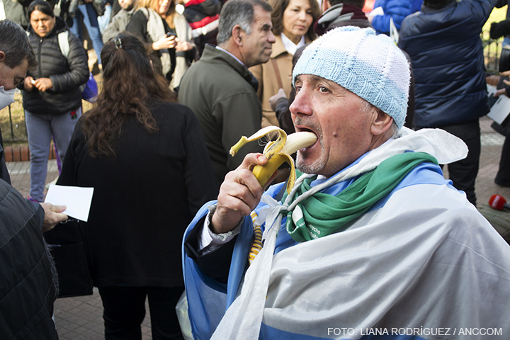 Hombre comiendo una banana en primer plano de fondo mucha gente concentrada.