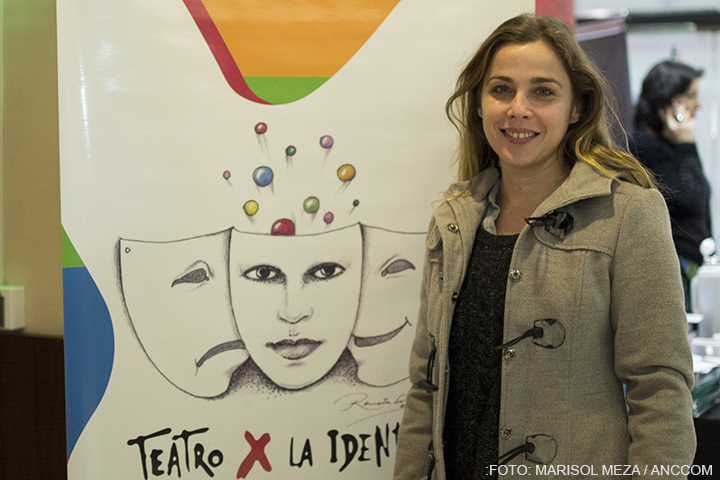 La actriz Melina Petriella se encuentra en primer plano, detrás de ella un cartel con el logo de teatro por la identidad.