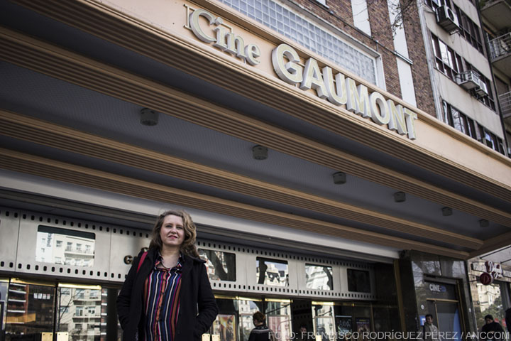 Una mujer parada en frente de la fachada de un cine, en el cartel del nombre del mismo se lee: "Cine Gaumont"