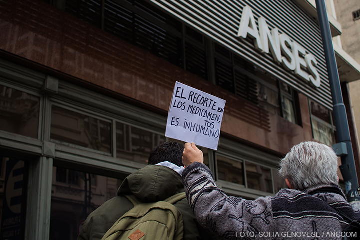 Un señor de espaldas en la puerta de ANSES levanta un cartel en el que se lee: "El recorte en los medicamento es inhumano".