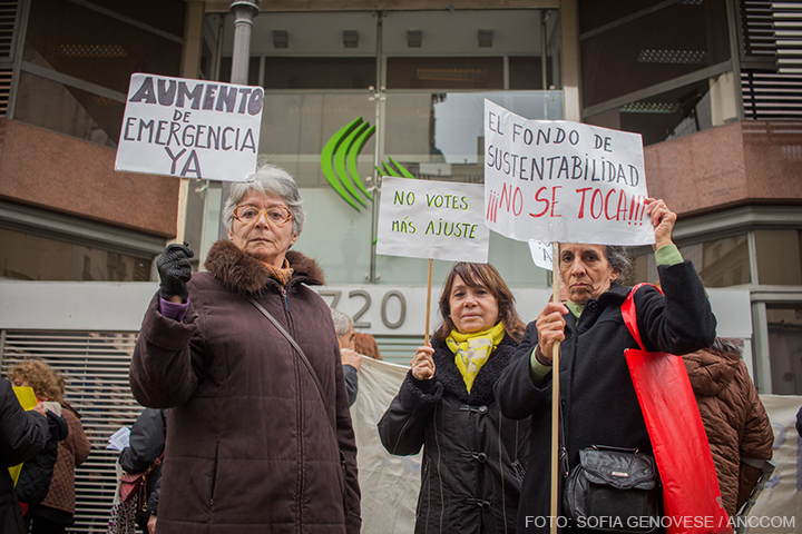Tres señoras levantan carteles de reclamo en los que se lee: "Aumento de emergencia ya", "no votes más ajuste" y "el fondo de sustentabilidad no se toca".