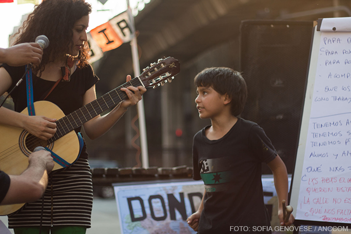 Una mujer con una guitarra y un niño junto a ella la mira.