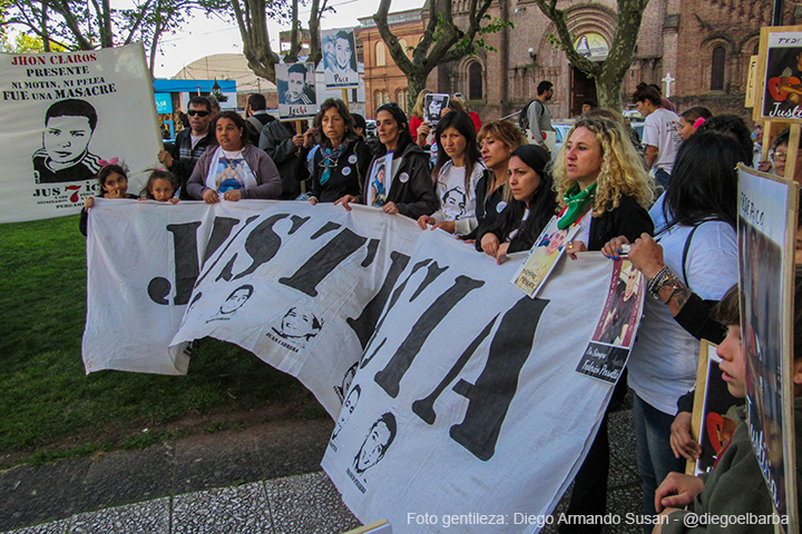Familiares de las víctimas sosteniendo una bandera con la inscripción "Justicia" en el frente.