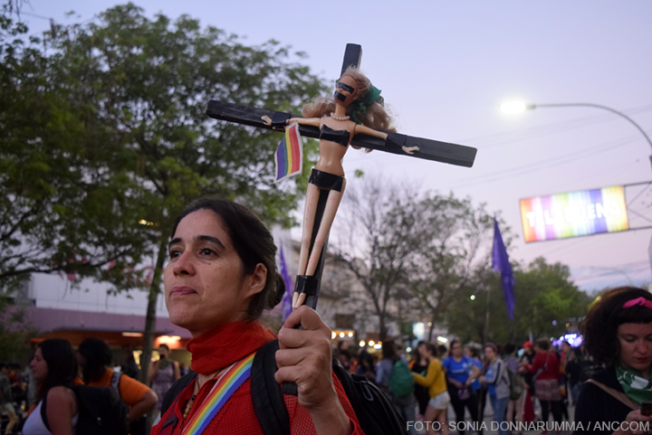 Mujer sosteniendo una muñeca crucificada. 