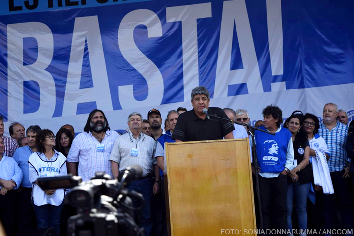 Pablo Moyano dando su discurso en la manifestación contra la reforma laboral impulsada por el gobierno. Atrás suyo estan parados otros sindicalistas y una bandera que dice "Basta!".