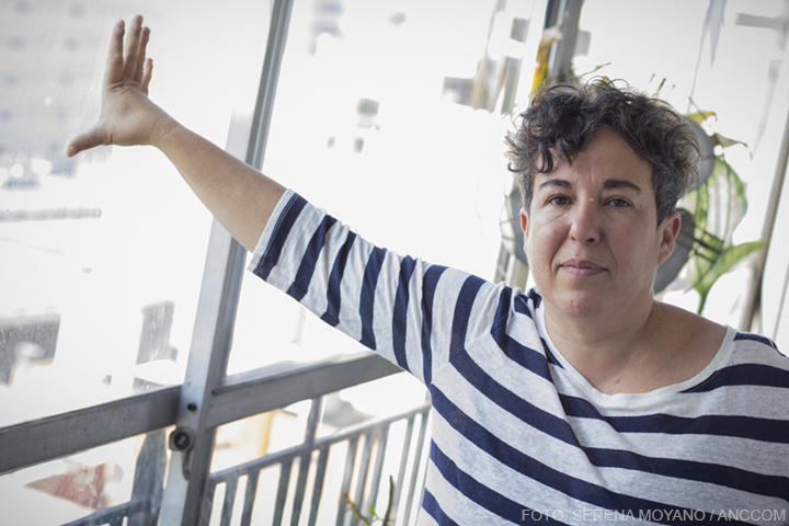 La escritora Gabriela Cabezón Camara fija su mirada en la cámara mientras posa una mano sobre una de las ventanas de su casa.
