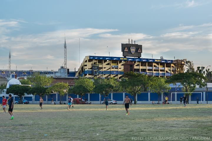 La imagen muestra el terreno en disputa siendo utilizado por jóvenes que juegan un partido de fútbol.