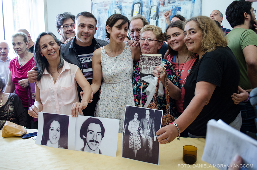 Adriana, junto a su abuela y familiares, sosteniendo imagenes de sus padres Violeta Ortolani y Edgardo Garnier.