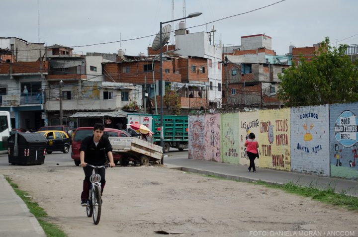 Un chico en bicicleta en el barrio del Bajo Flores, de fondo se ven pintados varios murales.