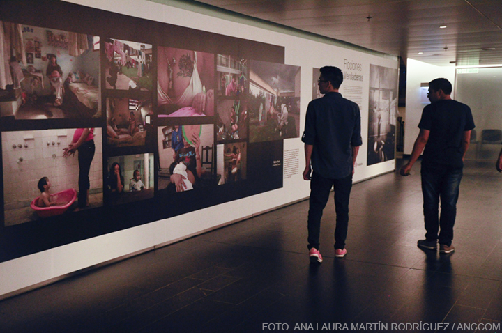 Dos chicos caminando por los pasillos del CCK observando una pared con imagenes, en el Festival de no Ficcion.