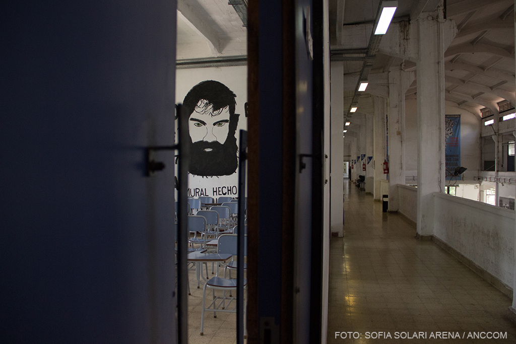 imagen de un pasillo y una puerta entornada que deja ver la imagen del rostro de Santiago Maldonado en la pared.