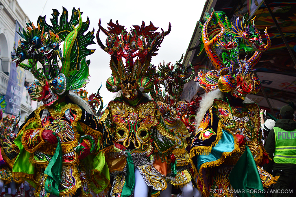 Tres integrantes del Carnaval de Oruro portan grandes disfraces muy coloridos.