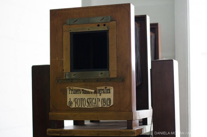 Una cámara fotográfica antigua que tiene un cartel pegado que dice "primera cámara fotográfica de FOTO SEGAL"