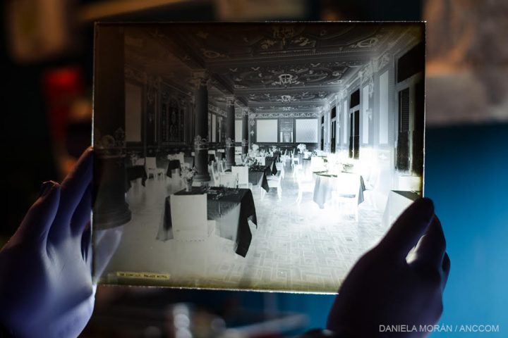 Dos manos sosteniendo una placa de vidrio del negativo de una fotografía tomada por Harry Grant Olds