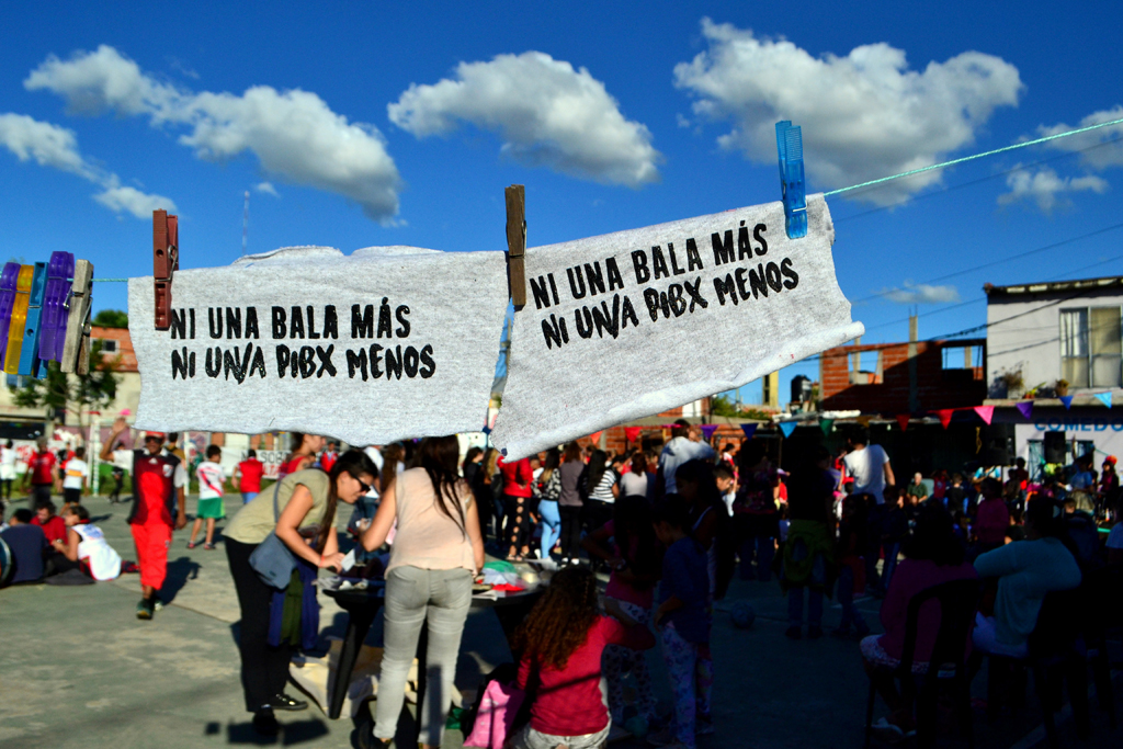 durante el Festival Caravana por la Infancia Digna, padres y niños reunidos. Se ven dos banderas que dicen "Ni una bala más, ni un/a pibx menos"