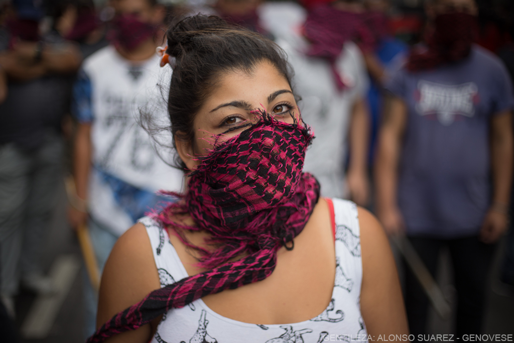 una mujer tapandose el rostro con un pañuelo en el contexto de una movilización.