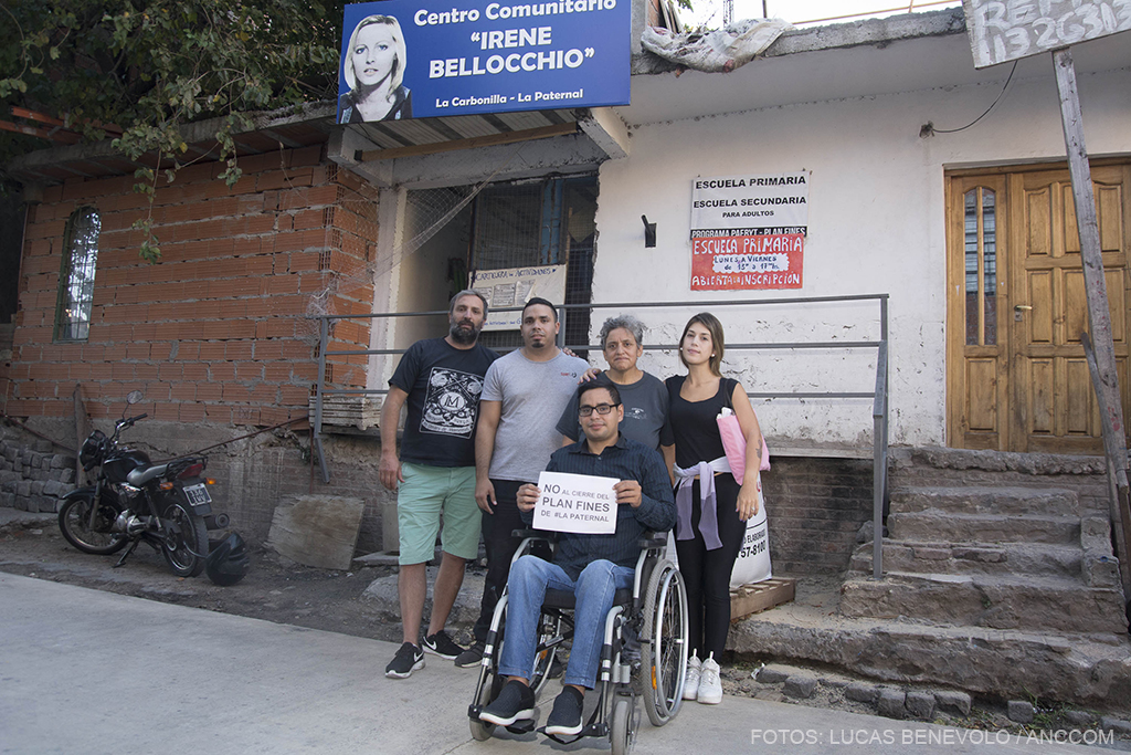 imagen de 5 miembros en la puerta del centro comunitario "Irene Bellocchio" con un cartel que dice "no al cierre del plan fines".