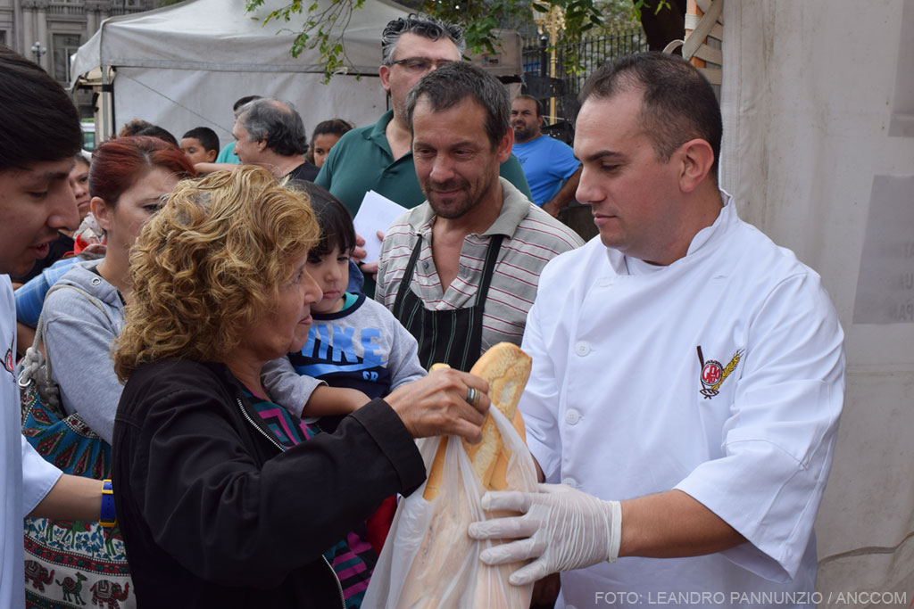 Un panadero entrega una bolsa con pan a una señora que se acercó al "panazo".