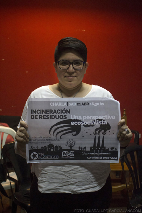 Natalia Cruz, de INTI, sostiene un cartel sobre una charla que se dará acerca de la incineración de residuos