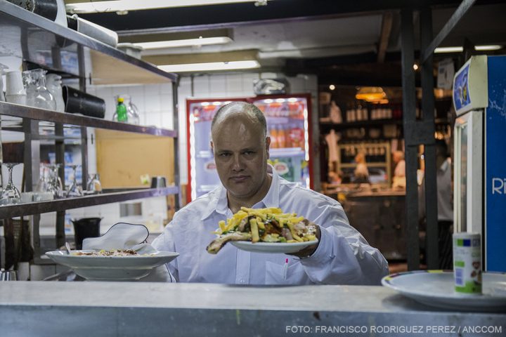 Rosendo, mozo de la Cooperativa Battaglia, lleva platos con comida en el restaurante.