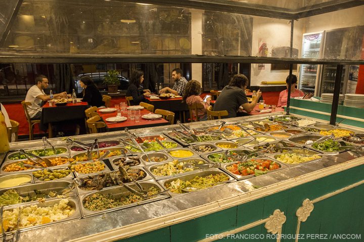 Restaurante Alé Alé, comida para servirse y gente sentada en mesas detrás.