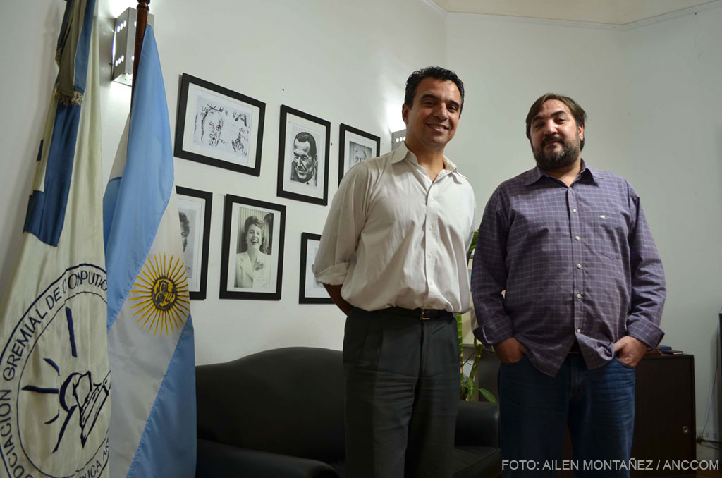 Ezequiel Tosco, de AGC, posa junto a la bandera argentina y a la de su gremio en su oficina.