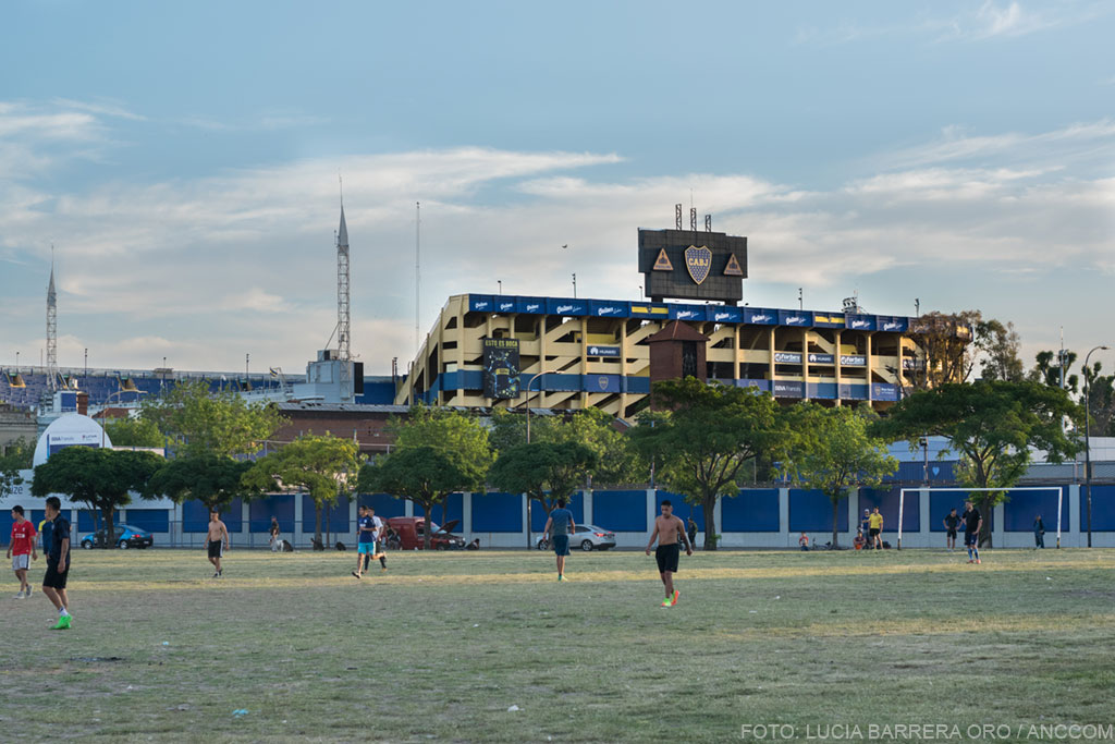 Chicos jugando al fútbol en los campitos de Casa Amarilla. Detrás, la Bombonera.