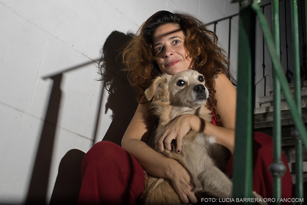 Zuleika Esnal sentada en la escalera del patio de su casa junto a su perro.