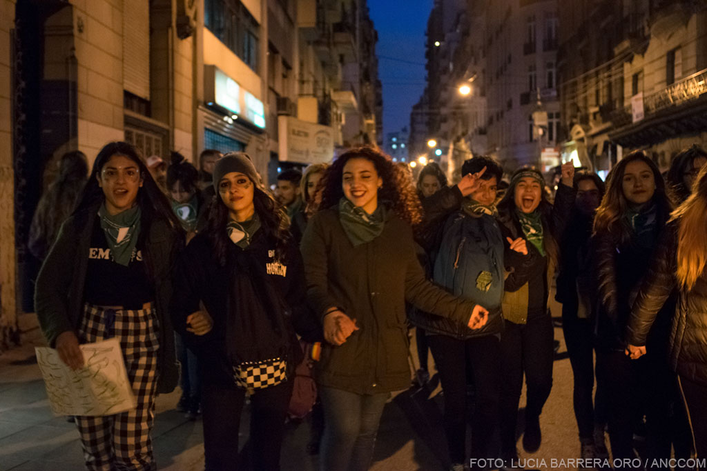 Mujeres jóvenes marchando tomadas de las manos y con sus pañuelos verdes.