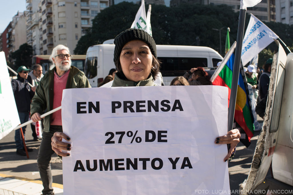 Mujer sosteniendo un cartel de reclamo salarial.