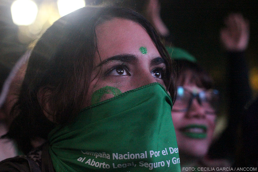 Cara de mujer en primer plano, con la mitad de su cara tapada por el pañuelo verde.