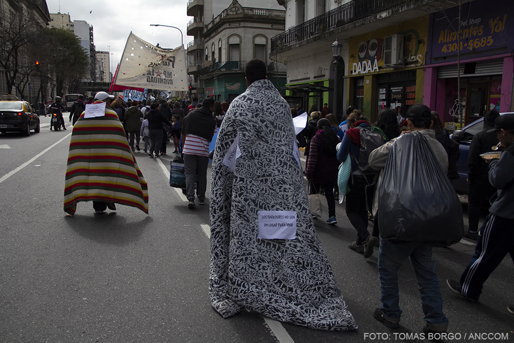 Hombres marchando en la calle cubiertos con mantas