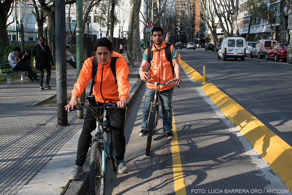 Dos trabajadores sobre sus bicicletas mirando a la cámara de frente.