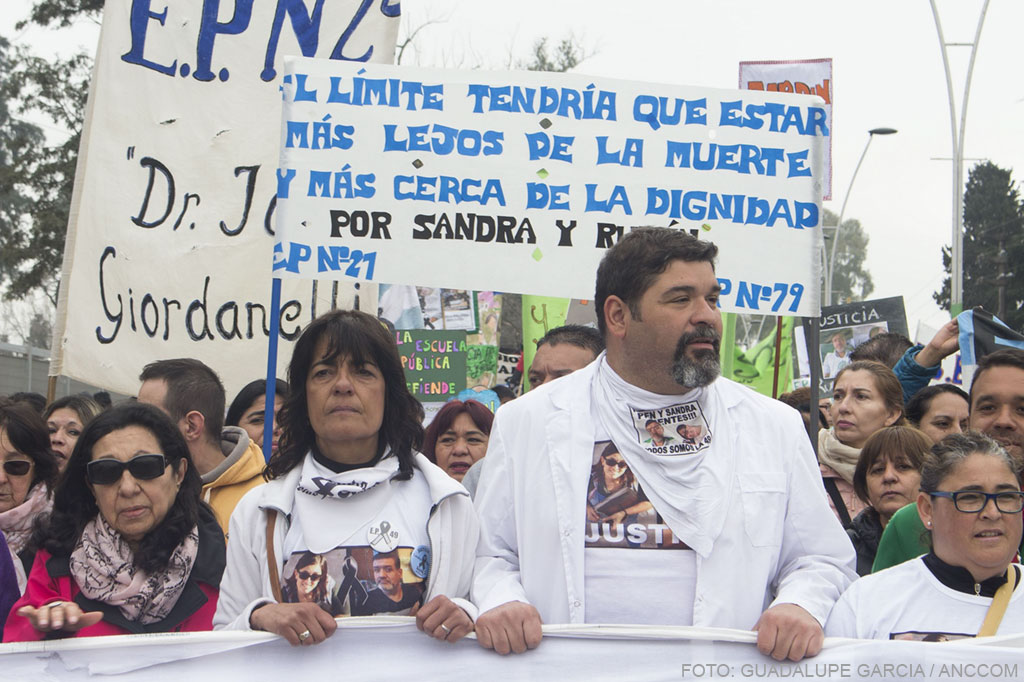 Docentes hombres y mujeres sosteniendo la pancarta, al frente de la marcha.